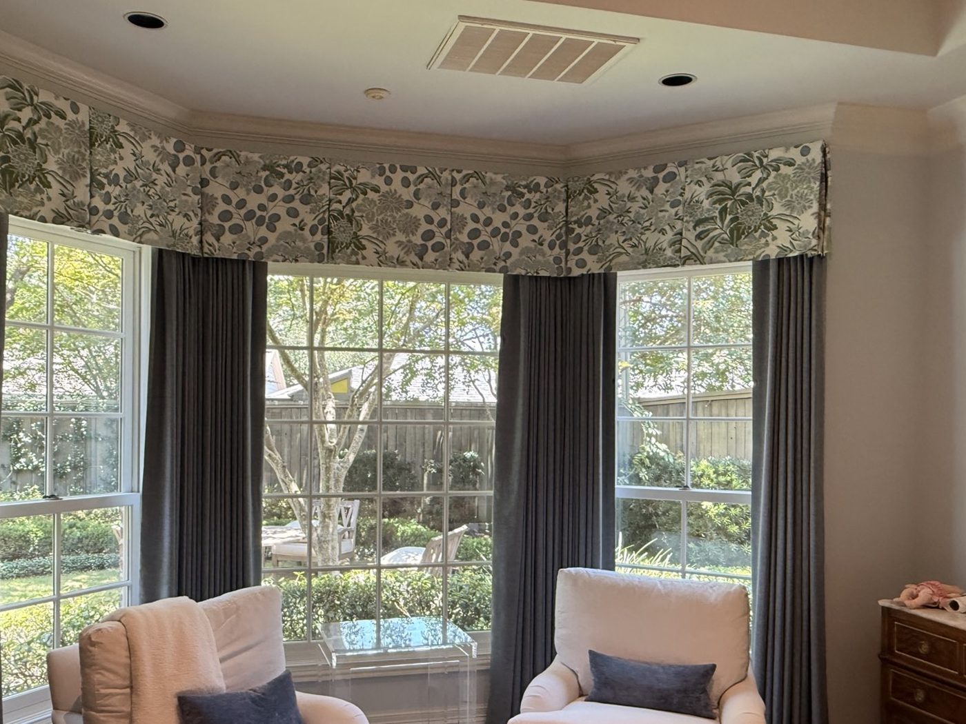 Floral shaped valance over gray drapery on a bay window